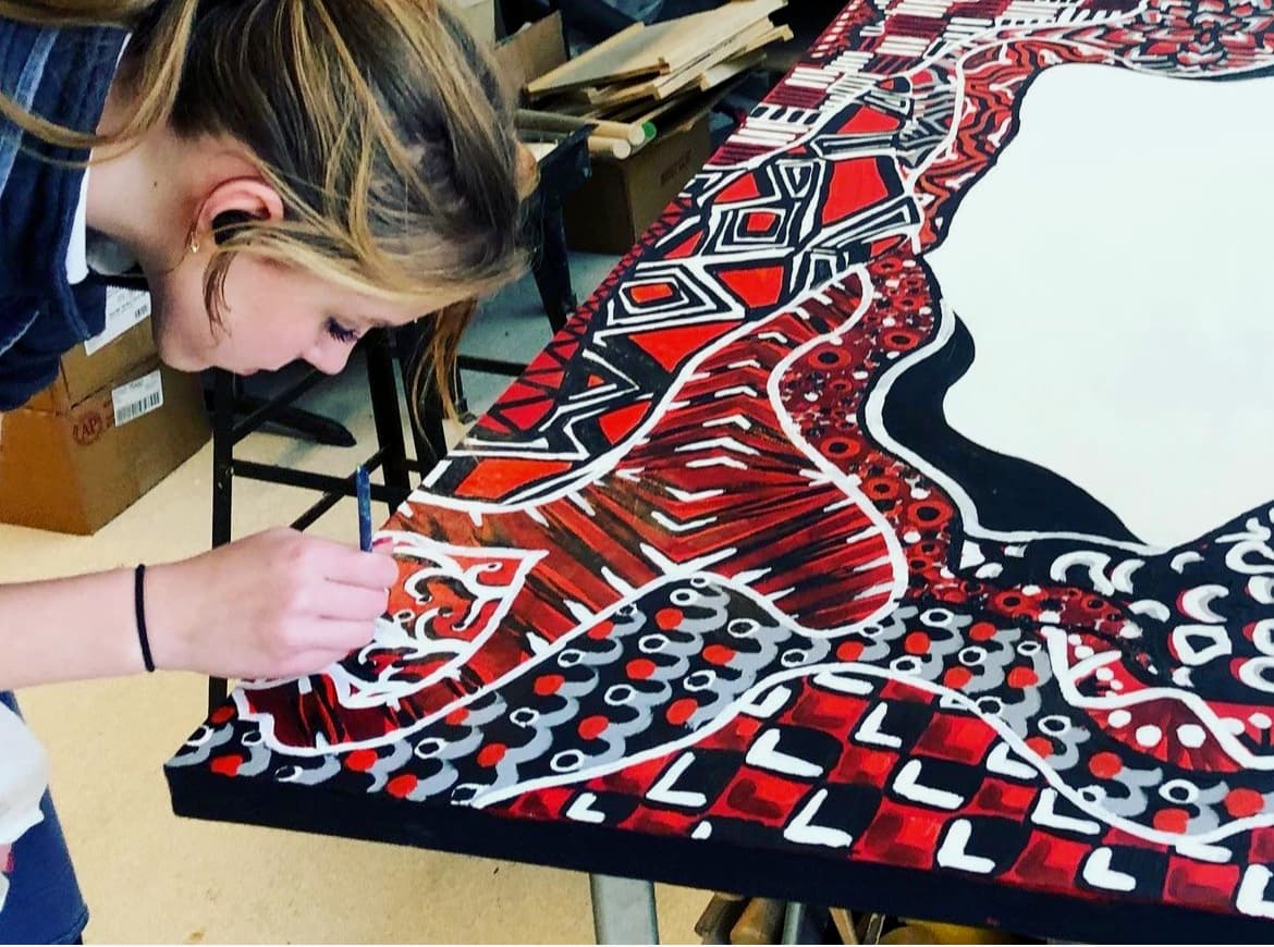 A St. Mary’s student painting a large red, black and white mural