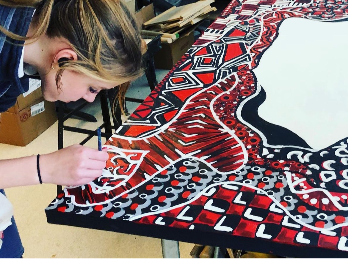 A St. Mary’s student painting a large red, black and white mural