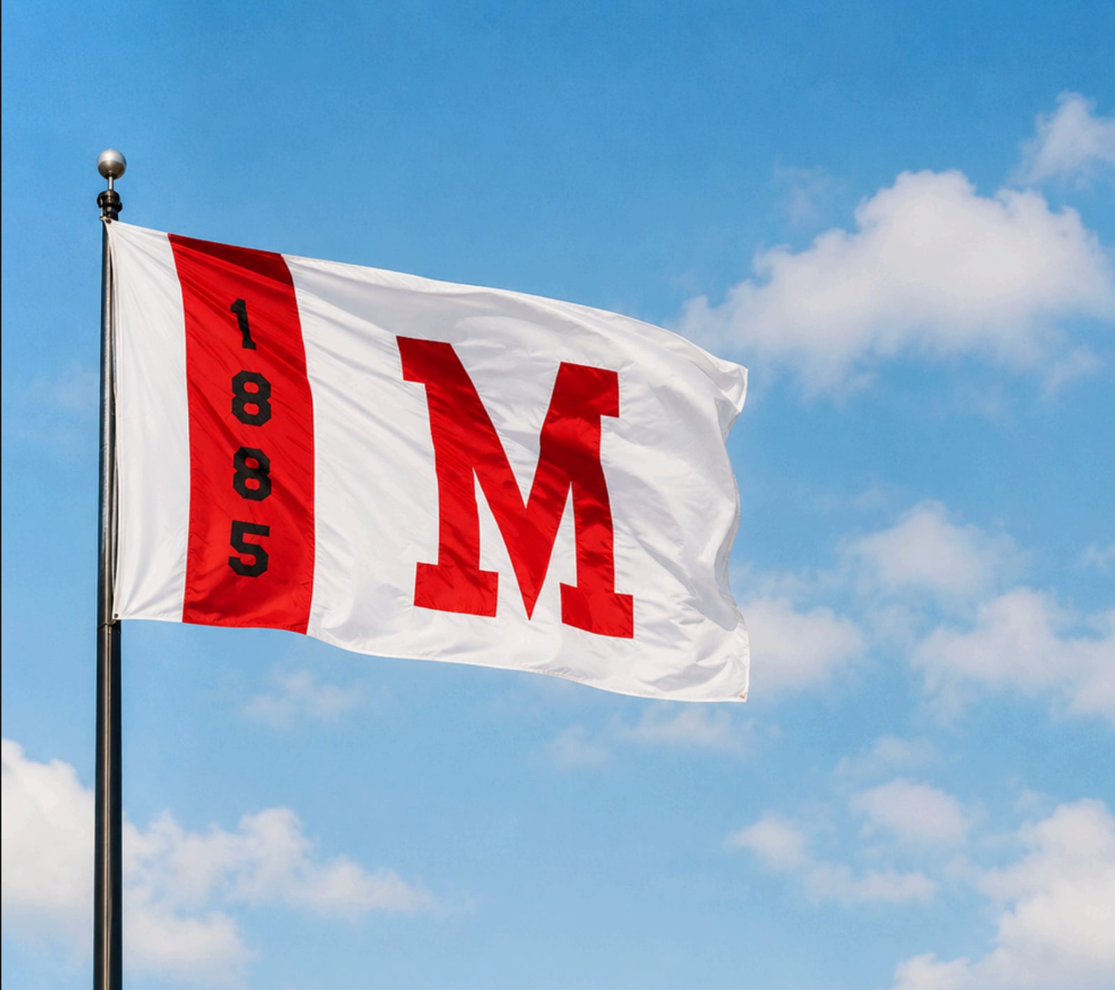 St. Mary’s flag with a red M and the year 1885 flying against a blue sky